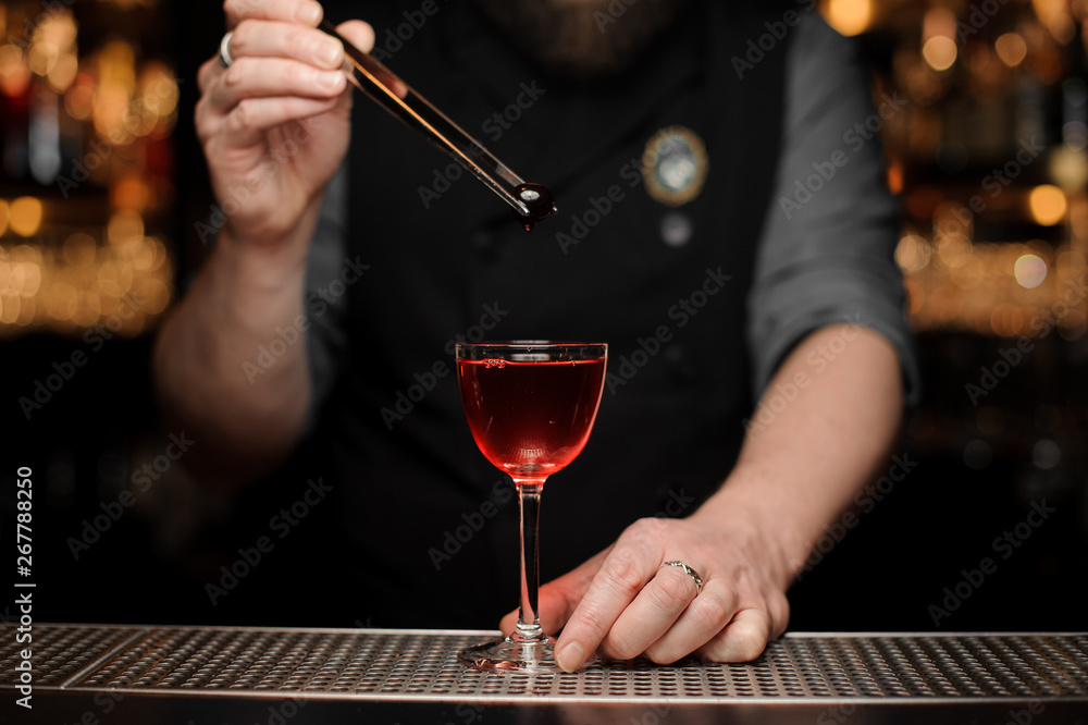 Close-up of bartender dropping cherry in alcohol drink