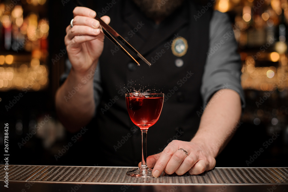 Close-up of bartender adding cherry in alcohol drink