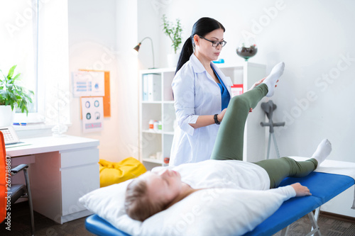 Focused long-haired physical therapist being involved in examination procedure