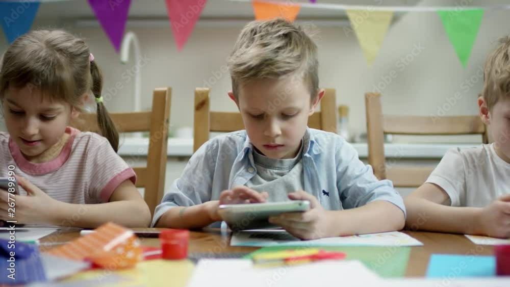 children make preparation for fiesta while one of them play in the tablet with overrun camera children make preparation for fiesta while one of them play in the tablet with overrun camera