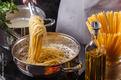 young woman in a gray apron preparing pasta