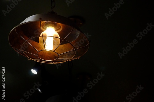 A modern lamp hanging from the room ceiling and glowing in the dark night