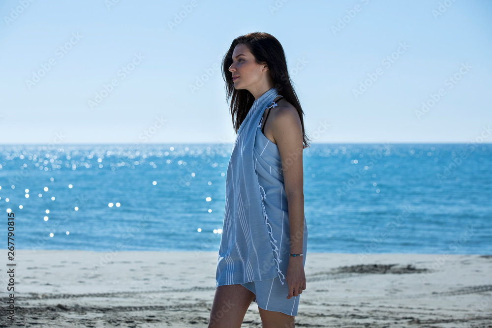 Pretty young girl wrapped in beach towel posing to the camera. Full length photo shoot and wonderful hair. Healthy, beauty and summer holiday concept. Pretty young girl wrapped in beach towel posing to the camera. Full length photo shoot and wonderful hair. Healthy, beauty and summer holiday concept.