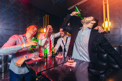 Group of smiling male friends having fun in night club