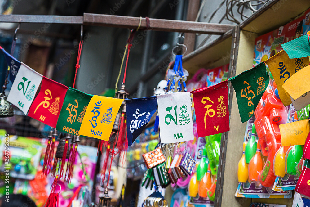 Naklejka premium Colorful Tibetan buddhist prayer flags displayed in shop for sale along with other gift items, nepal - Image