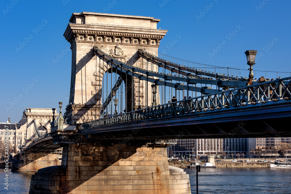 Obraz premium Hungary, Budapest: Side view of famous Szechenyi Chain Bridge pillar above Donau Danube river in the city center of the Hungarian capital with blue sky in the background - concept architecture travel