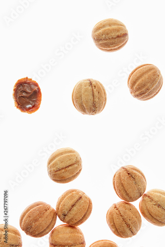 Falling cookies walnuts with milk cream on a white background.