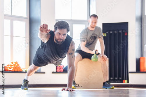 Two friends of men athletes doing strength training and interval workout in the gym. Concept of a healthy lifestyle and trend for sports