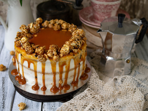 Carrot cake with salted caramel and cheesecake inside, decorated with popcorn and caramel. Retro style, vintage. Selected focus, close up. Cake for birthday.