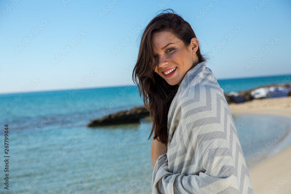 Pretty young girl wrapped in beach towel poses on camera with a smiling face. Portrait shot and wonderful hair. Beauty and summer concept. Pretty young girl wrapped in beach towel poses on camera with a smiling face. Portrait shot and wonderful hair. Beauty and summer concept.