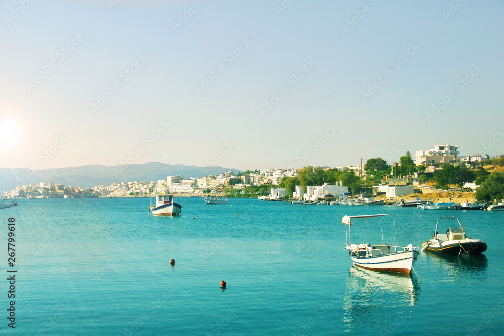 Town by the Mediterranean sea in turquoise lagoon, fishing boats in turquoise water on the clear sky background, summer landscape in retro style, tourism concept
