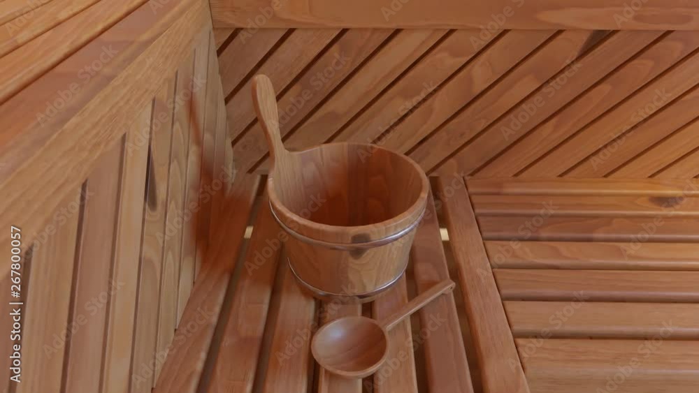 Wooden Finnish sauna accessories. Water bucket with a wooden ladle in a