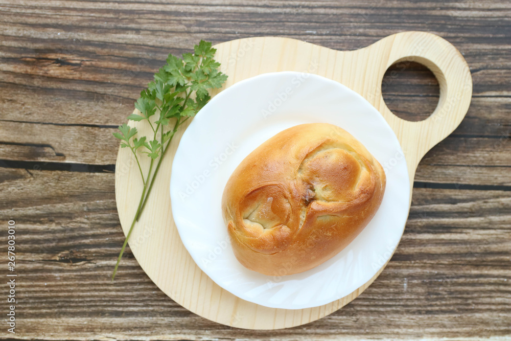Tradisional russian Pie with onion and egg on a white plate on a round cutting board laying on a wooden table, top view, horizontal Tradisional russian Pie with onion and egg on a white plate on a round cutting board laying on a wooden table, top view, horizontal