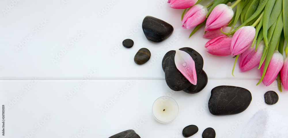 Spa setting with tulips , black stones and towel on white wood background. Spa setting with tulips , black stones and towel on white wood background.