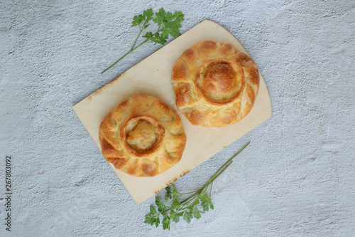 Two traditional russian chicken pies called kurnik on a wooden cutting board laying on a grey background, top view, horizontal photo