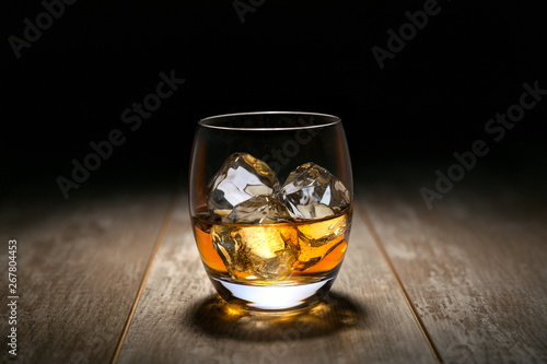 Fotografie Whiskey, Rum, Cognac liquor on ice in a round rocking tumbler glass, on vintage