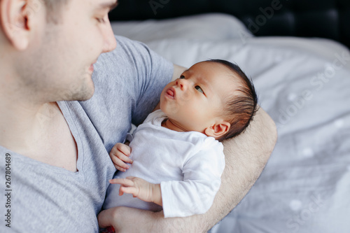 Closeup of young Caucasian father with newborn mixed race Asian Chinese baby. Male man parent holding child daughter son. Authentic lifestyle touching moment. Single dad family