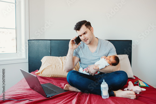 Caucasian father dad with newborn mixed race Asian Chinese baby working from home. Male man parent holding child daughter son talking over phone. Single dad family. Genderblend concept photo