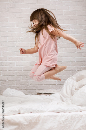 cute little child girl fooling around in bed. child jumping on bed