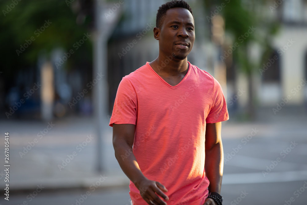 African american man in living coral t-shirt walking at city street, casual style, crossing a road African american man in living coral t-shirt walking at city street, casual style, crossing a road