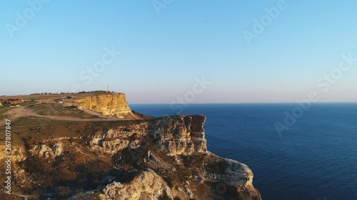 Aerial view of people standing on a large cliff against blue clear sky and blue sea water. Shot. Beautiful view from above photo