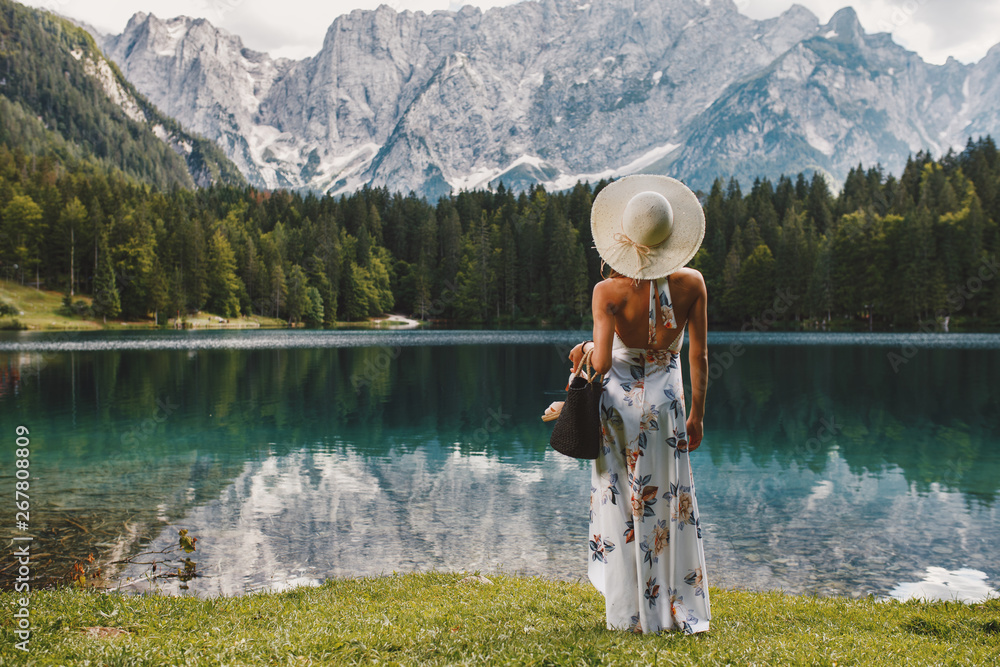 Young beautiful woman in a dress and hat near the lake - obrazy, fototapety, plakaty 