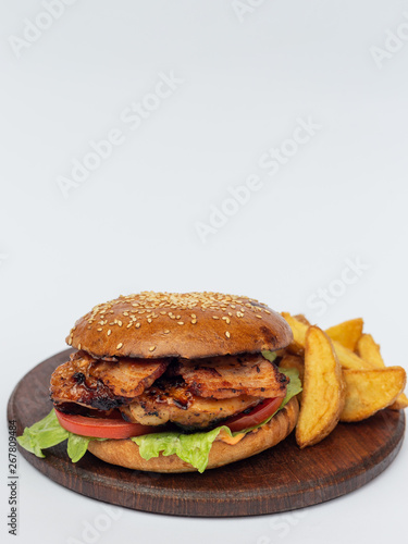 Classic american hamburger on a wooden board with fried potatoes, white background