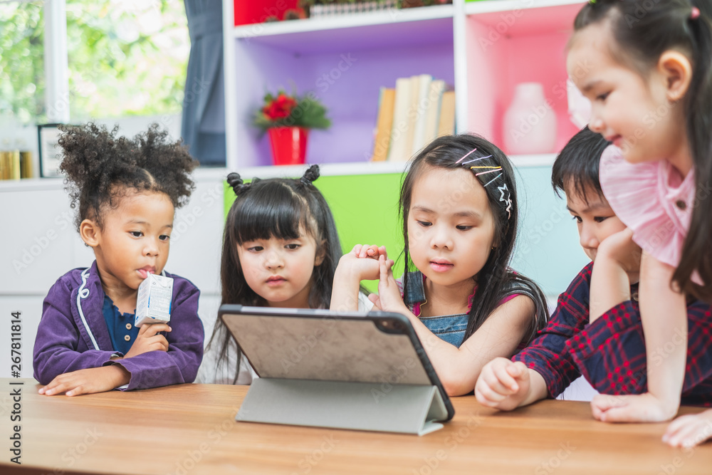 Group of diversity cute kids watching on tablet for lesson in classroom, education concept Group of diversity cute kids watching on tablet for lesson in classroom, education concept