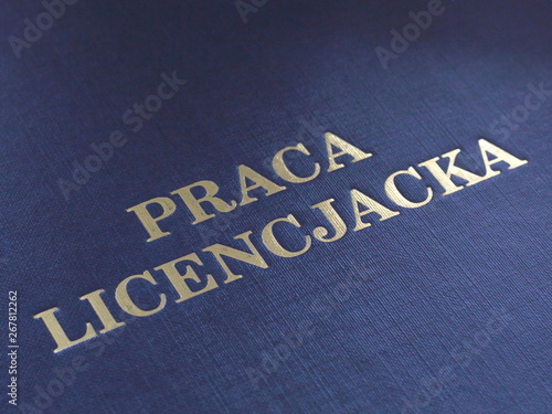 Closeup of a cover of Polish bachelor dissertation. Gold lettering on navy blue cover. photo