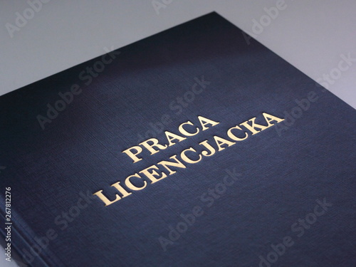Closeup of a cover of Polish bachelor dissertation. Gold lettering on navy blue cover.