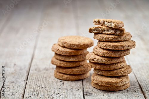 Two stacks of fresh baked oat cookies on rustic wooden table background.