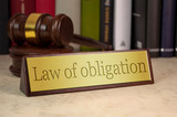 Golden sign with gavel on a deskop with law of obligation