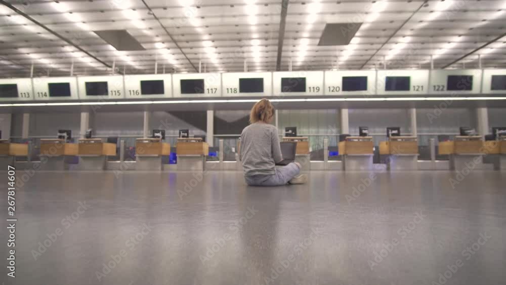 Girl sits in the terminal on the floor of the airport works with a laptop while waiting for the flight. Girl sits in the terminal on the floor of the airport works with a laptop while waiting for the flight.