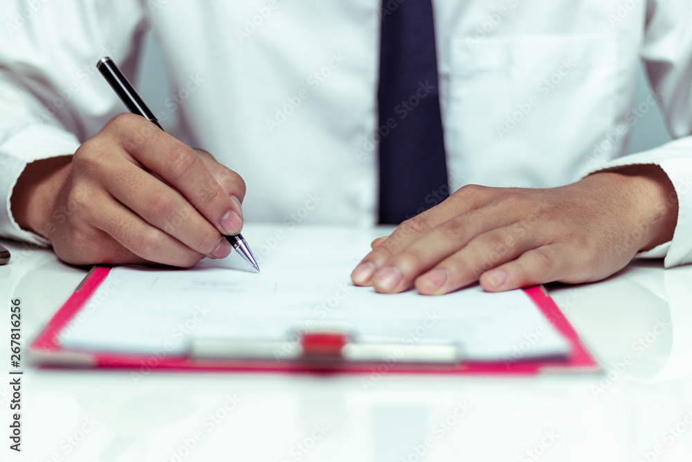 Businessman signing a document in office Businessman signing a document in office