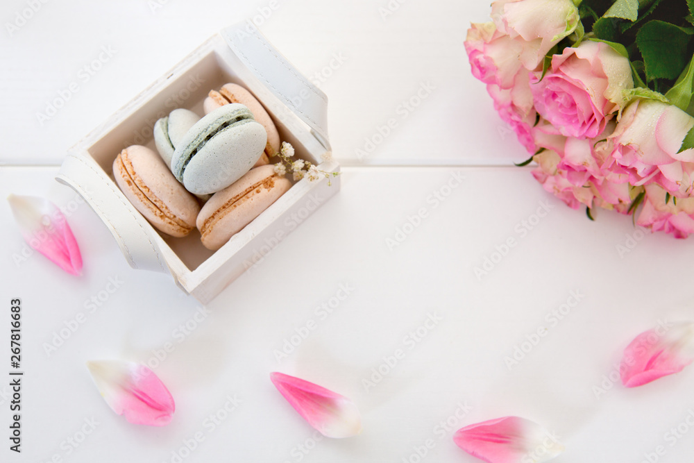 Pink roses and macaron cookies in the basket on white background. Pink roses and macaron cookies in the basket on white background.