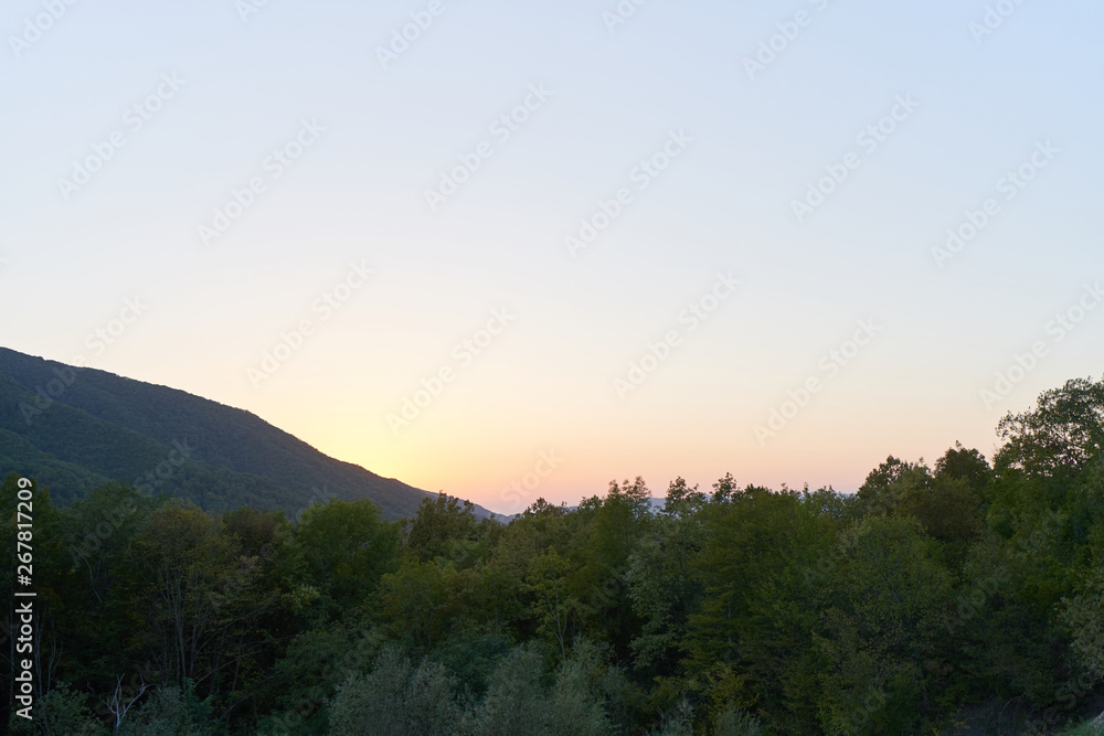 Evening landscape with mountains overgrown with trees against a sunset. Beautiful mountains around Geledzhik, Russia