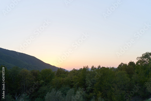Evening landscape with mountains overgrown with trees against a sunset. Beautiful mountains around Geledzhik, Russia