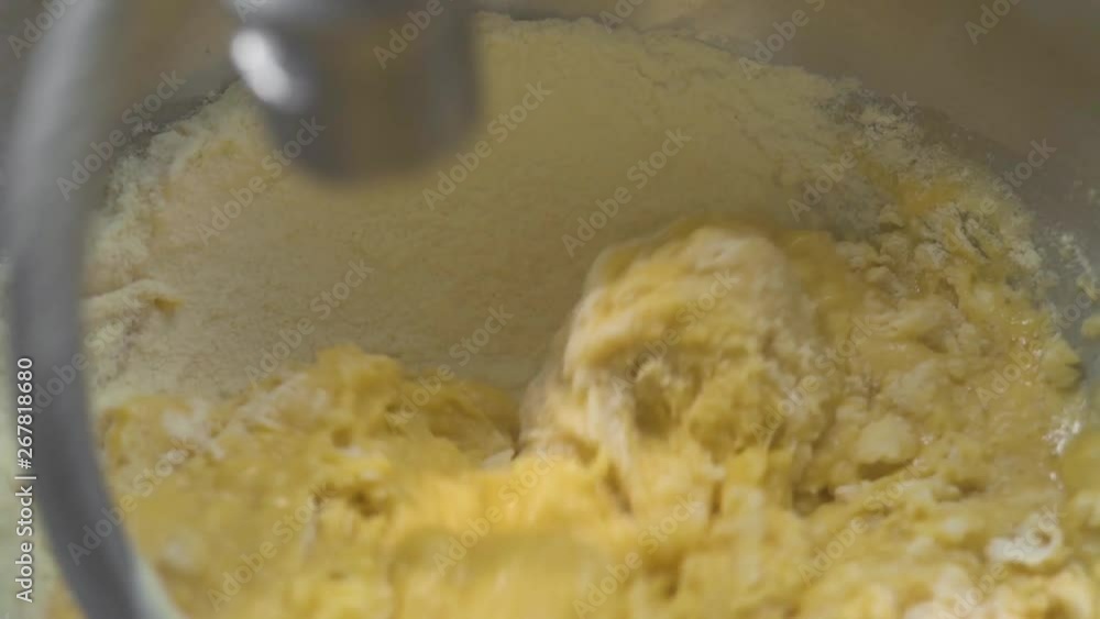 Close up kneading dough for pastry in kitchen mixer. Kitchen kneader machine mixing dough in bakery. Ingredients for baking homemade bread. Cooking food concept. Close up kneading dough for pastry in kitchen mixer. Kitchen kneader machine mixing dough in bakery. Ingredients for baking homemade bread. Cooking food concept.
