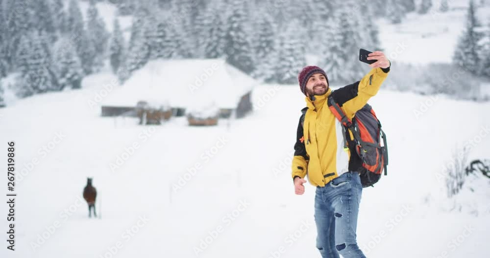 Charismatic tourist taking pictures selfies with a beautiful horse in the winter day in the middle of mountain , tourist are equipped with all travel staff Charismatic tourist taking pictures selfies with a beautiful horse in the winter day in the middle of mountain , tourist are equipped with all travel staff