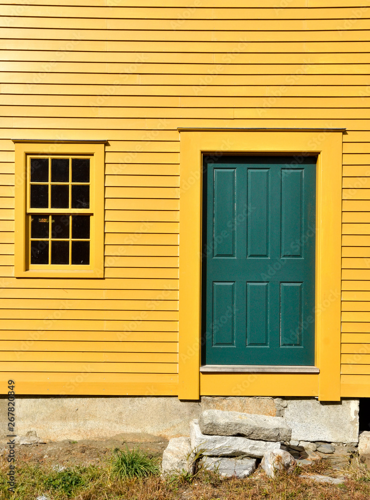 green door on yellow exterior farmhouse wall with window