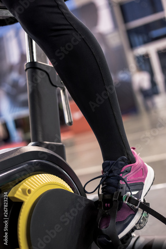 Close up of girl foot on black and yellow sport bicycle in the gym for training.