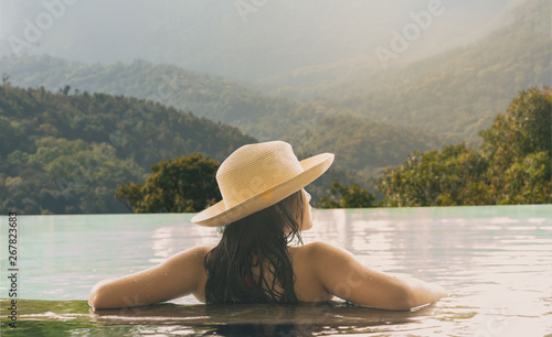 Rear view of happy lifestyle women relaxation and enjoy in the pool looking outdoors mountain nature. Women together on summer and vacations travel to luxury resort. Summer and Holiday Concept © peampath