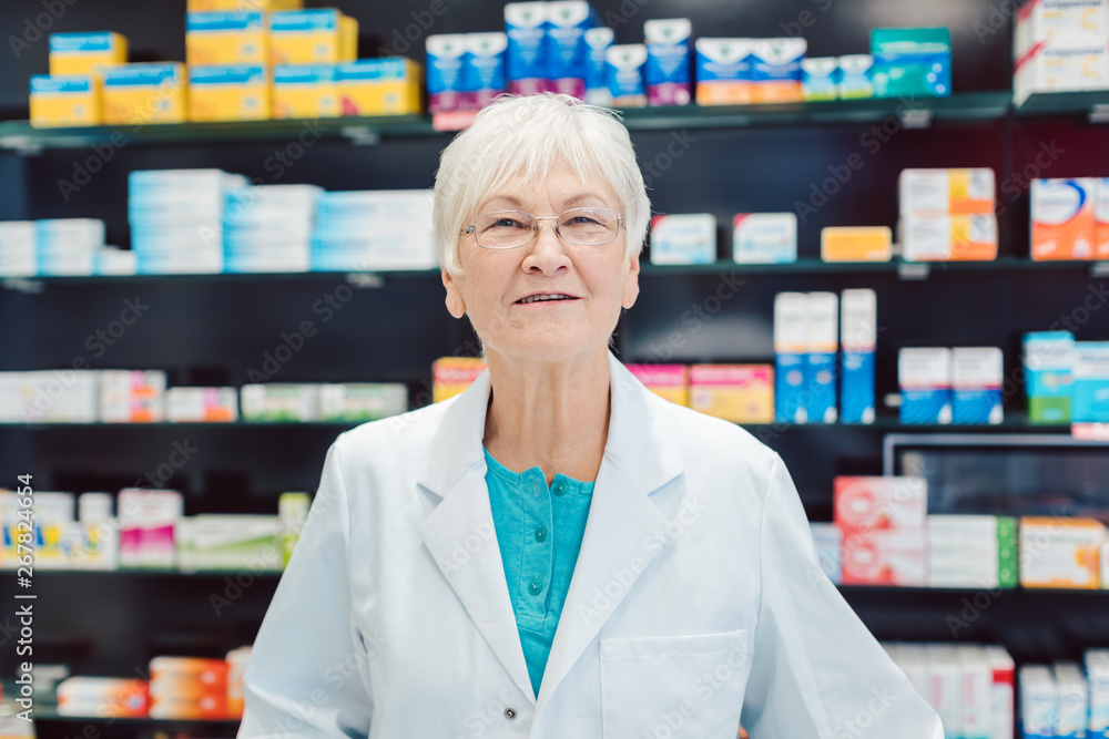 Experienced senior pharmacists in front of shelves in pharmacy