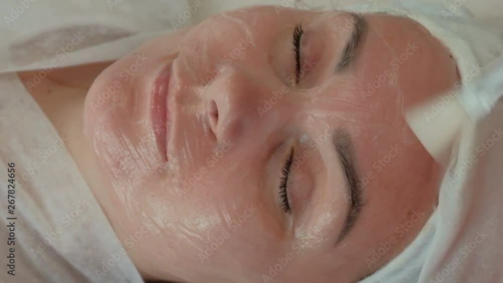 Beautiful girl on the procedure in the beauty salon. Rejuvenation and professional skin care. The beautician applies a nourishing gel to the female face with a brush. Beautiful girl on the procedure in the beauty salon. Rejuvenation and professional skin care. The beautician applies a nourishing gel to the female face with a brush.