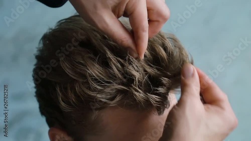 barber makes hair styling with hair gel for customer after haircut