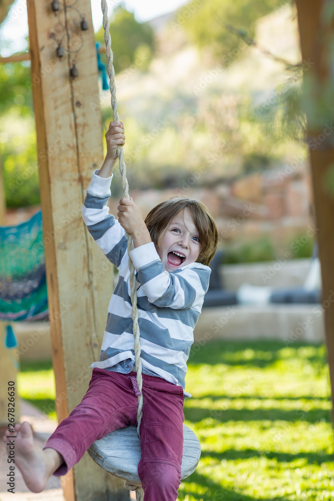 5 year old boy playing on swing under porch 5 year old boy playing on swing under porch