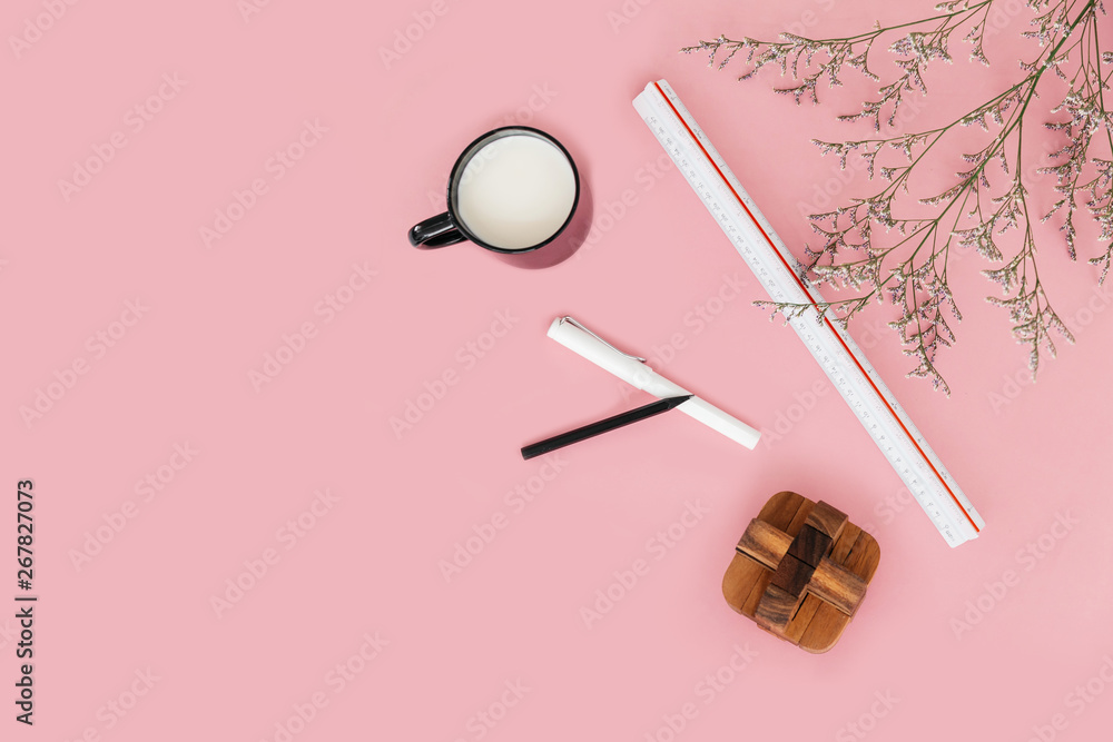 Pink color background with flower branches, scale ruler, a cup of milk, pen, pencil and wooden block on the right side. Architect and designer background with copy space. Pink color background with flower branches, scale ruler, a cup of milk, pen, pencil and wooden block on the right side. Architect and designer background with copy space.
