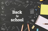 Stationery on chalkboard top view with doodle drawing and BACK TO SCHOOL text. banner background.