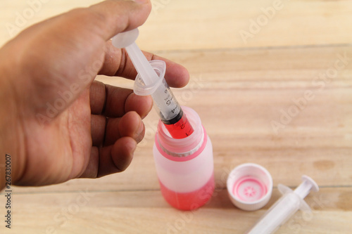 Man hand using syringe to draw sucking red medicine from bottle. Preaparing for medication. Medical concept photo