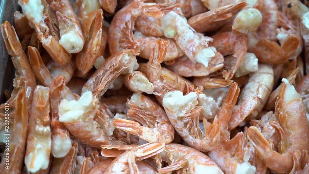 Lots of tasty big frozen red shrimps close up in the supermarket fridge. Seafood stand in a metal tray on ice in store. Fish shop. Lots of tasty big frozen red shrimps close up in the supermarket fridge. Seafood stand in a metal tray on ice in store. Fish shop.